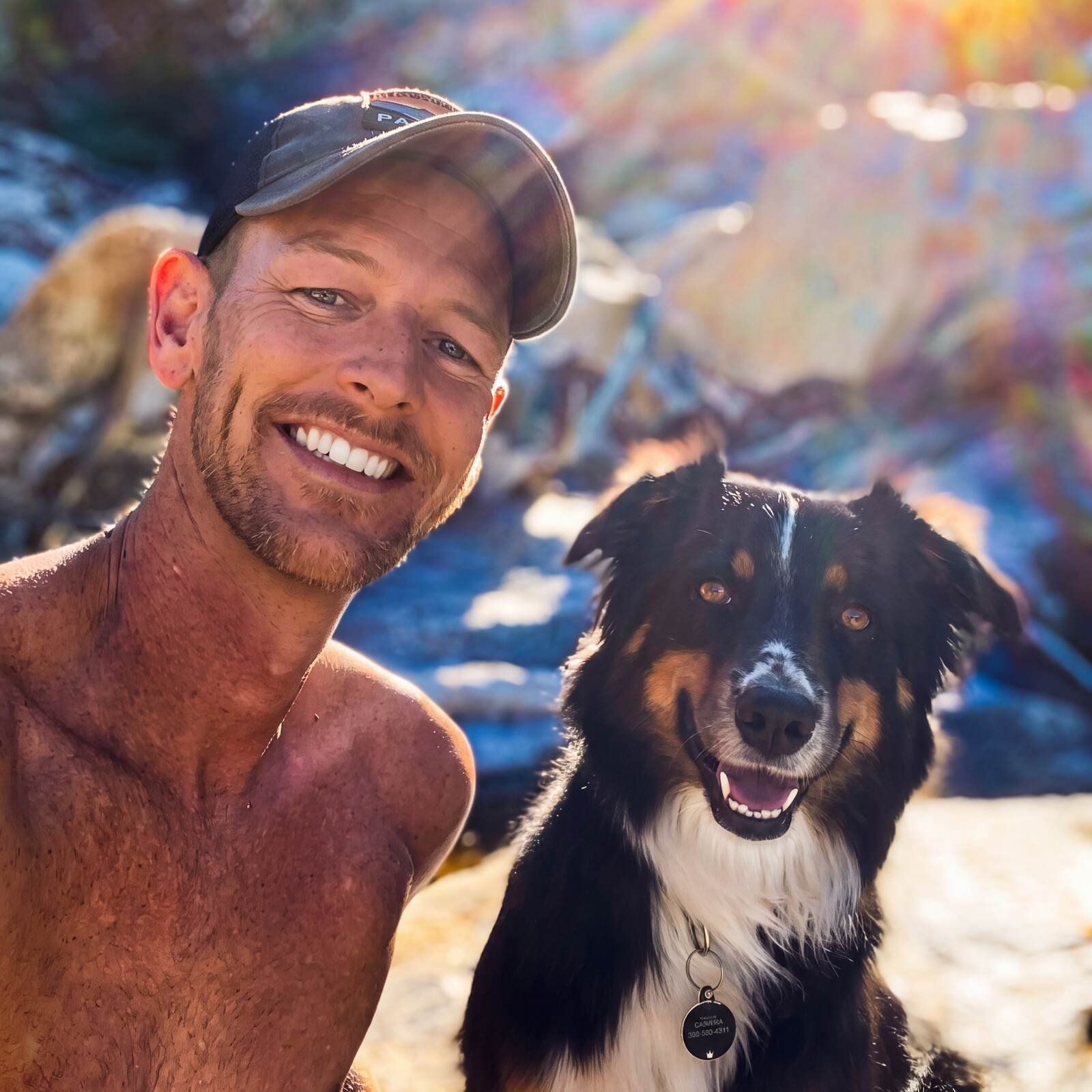 Kira posing for a sunny selfie with her other dad, both smiling outdoors